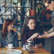 friends pay for lunch in a restaurant with their smartphone.