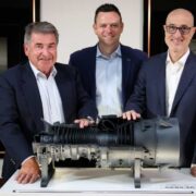 Three men with a model of a gas turbine.