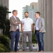 Three men standing on a street.