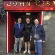 Three men standing outside a pub called Gibneys.