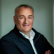 Man in navy jacket and white shirt.