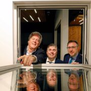 Three men examining a window being manufactured.
