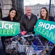 Two women and a man holding click green and shop clean banners over a shopping trolley filled with Irish goods.