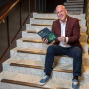 Man in wine sports jacket sitting on steps reading a report.