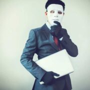 Man in suit hiding behind a mask.