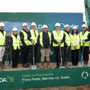 Large group of people in hi-vis and helmets on a building site.