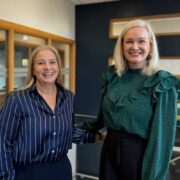 Woman in navy blouse and woman in green blouse.