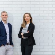 Man and woman in front of a wall.