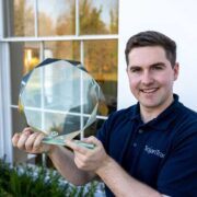 Man in t-shirt holding an award.