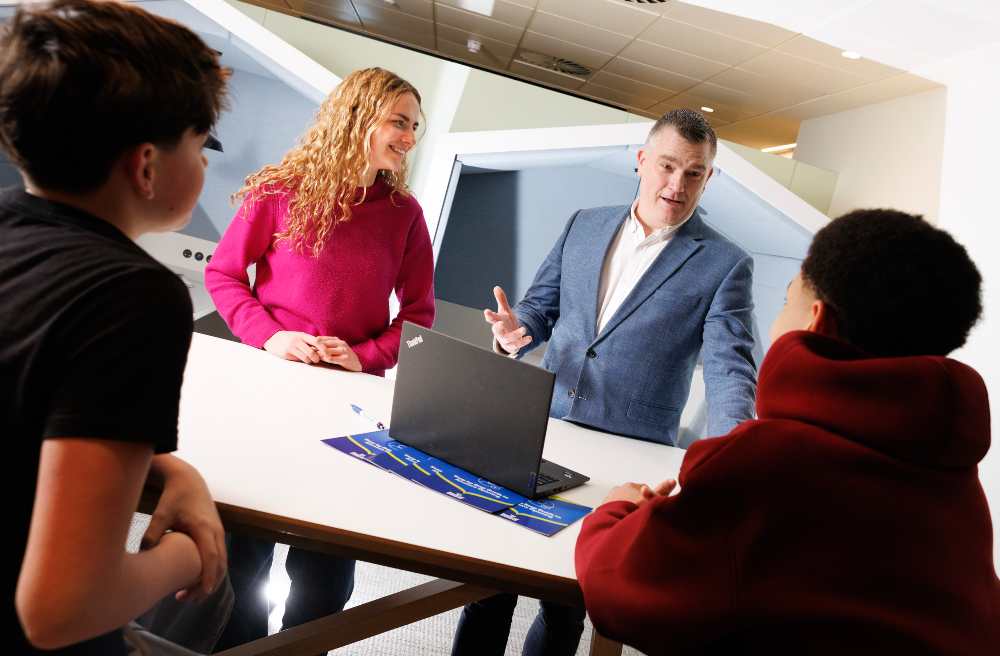 Man in suit talking with teenagers.