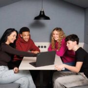 Woman talking with three teenagers at a desk.