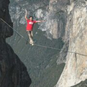 Man in red t-shirt walking a tightrope.