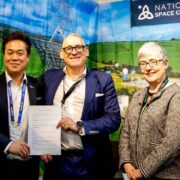 Two men holding a contract beside a woman.