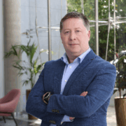 Man in blue sports jacket with arms folded.