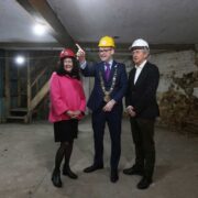 Two men and a woman wearing hard hats.