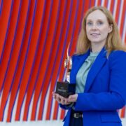 Woman in blue suit holding an award.