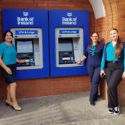 Three Bank of Ireland staff members stand beside new ATM machines.