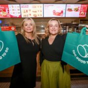 Two women in a Circle K service station holding green Too Good to Go bags.
