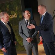 Three men speaking at an event.