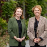 Two business women in a garden setting.