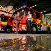 Two men talking in front of a fire engine.