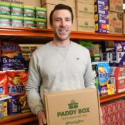 Man in grey sweatshirt holding a box.