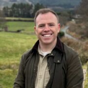 Man in green jacket out standing in a field.