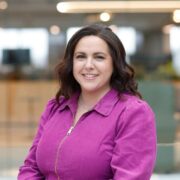 woman with dark hair wearing pink top.