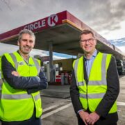 Two men in hi-vis jackets standing on a Circle K forecourt.