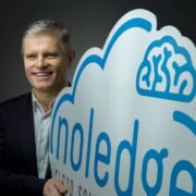 Man holding sign that says noledge in shape of cloud and brain.