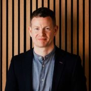 Man in black jacket and blue shirt.