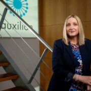 Fair-haired woman standing at a flight of stairs.