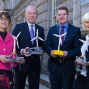 Two women and two men on a street in Dublin holding models of wind turbines.