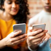 Young adults splitting a bill on their mobile devices.