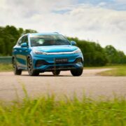 Blue electric SUV driving on a rural Irish road with greenery and trees in the background.