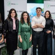Group photo of seven people standing indoors at a CIRCUL&Eacute;IRE event, positioned in front of branded CIRCUL&Eacute;IRE backdrop banners. The group stands side by side, dressed in business‑casual attire. Green lighting and event staging elements are visible in the background, suggesting a formal programme or launch setting related to circular economy innovation.