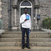 Young entrepreneur proudly holding his product standing on steps.