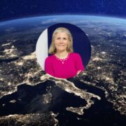 Circular portrait of a professional individual wearing a bright pink top, overlaid on a satellite-style night-time view of Europe with illuminated cities visible across the continent.