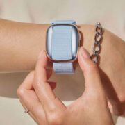 Close-up of the MyCelsius cooling bracelet worn on a woman’s wrist, showing the square cooling face and fabric strap, with the wearer adjusting the device by hand.