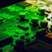 Close-up view of a green-lit printed circuit board showing AI semiconductor chips, capacitors and integrated components, illustrating advanced low-power AI hardware technology.