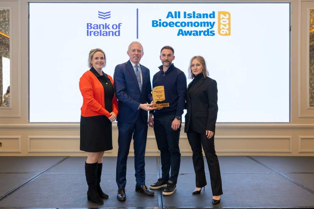 Four individuals standing on a stage in front of a large screen displaying Bank of Ireland and All Island Bioeconomy Awards 2025, with one individual presenting a trophy to another while two others stand alongside, in a formal awards ceremony setting.