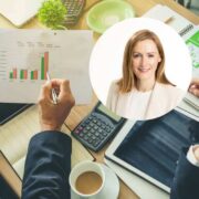 Two business professionals seated at a desk review printed financial charts showing bar graphs, with a calculator, tablet, coffee cup and notepad visible nearby; a circular inset portrait of a professional appears over the scene, suggesting commentary or analysis of business performance and rising costs.