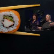 Close-up of a sushi roll held between chopsticks against a dark background, with an inset image showing two speakers at a Bank of Ireland podcast-style interview setup with microphones.