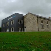 Future Cast innovation centre in Manorhamilton, Co Leitrim, showing a modern dark-clad extension beside a restored stone church building under cloudy skies.
