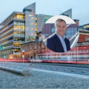 PwC office building in a modern urban streetscape with traffic light trails, overlaid with a circular portrait of a corporate professional against a blurred city background.