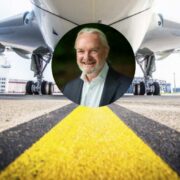 Close-up of a commercial aircraft on a runway, viewed from beneath the fuselage with landing gear visible, overlaid with a circular portrait of a person in business attire at the centre.