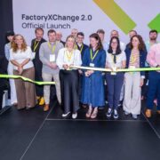 Representatives from the FactoryXChange 2.0 consortium take part in a ribbon-cutting ceremony at the programme's official launch event in Mullingar, marking the start of the next phase of Ireland's manufacturing innovation initiative. A large backdrop displays the FactoryXChange 2.0 logo and launch branding.