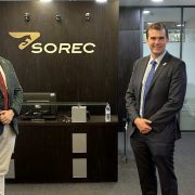 Two business executives stand in the reception area of SOREC headquarters in Morocco, beside a Moroccan flag and the SOREC corporate logo, highlighting international business collaboration, leadership and equestrian industry development.