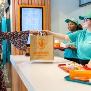 Customer collecting food at a Popeyes outlet operated by Applegreen in Ireland, supporting the company's expansion of roadside hospitality, EV hubs and retail services at the new Naas Ball M7 development in Co Kildare.