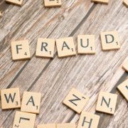 Wooden letter tiles spelling “FRAUD” scattered across a table, illustrating business fraud prevention, scam awareness, cybersecurity risks and AI-enabled financial crime facing SMEs.